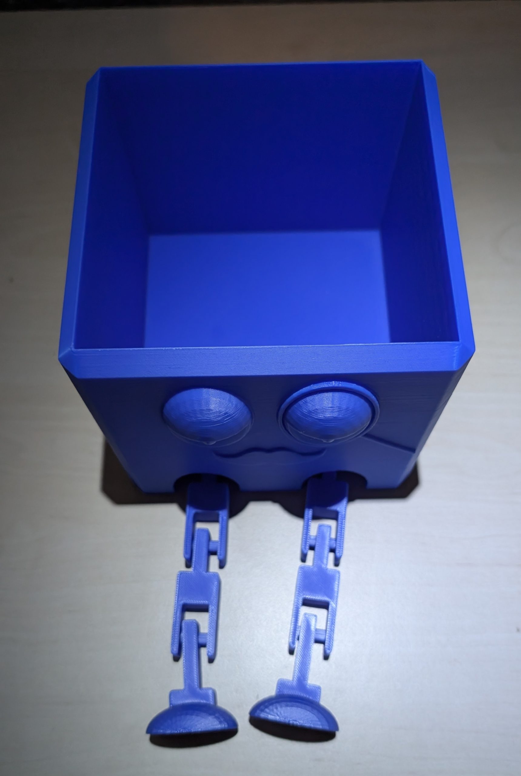 Eckiger Organizer in Blau mit Gesicht und beweglichen BeinenI